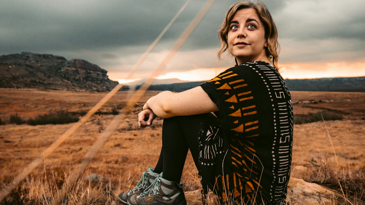 woman in black and white shirt sitting on brown rock during daytime