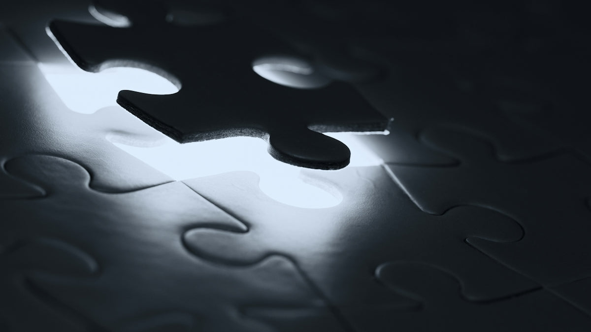 A single dark puzzle piece hovering above a matching empty slot