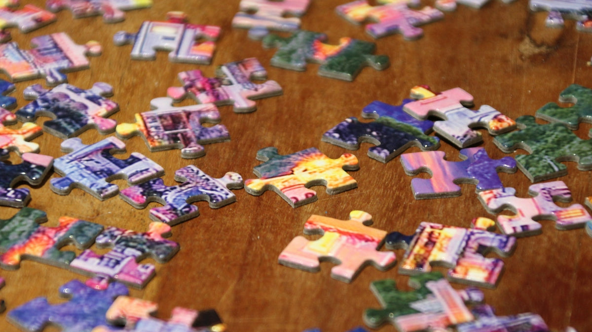 a wooden table topped with lots of puzzle pieces