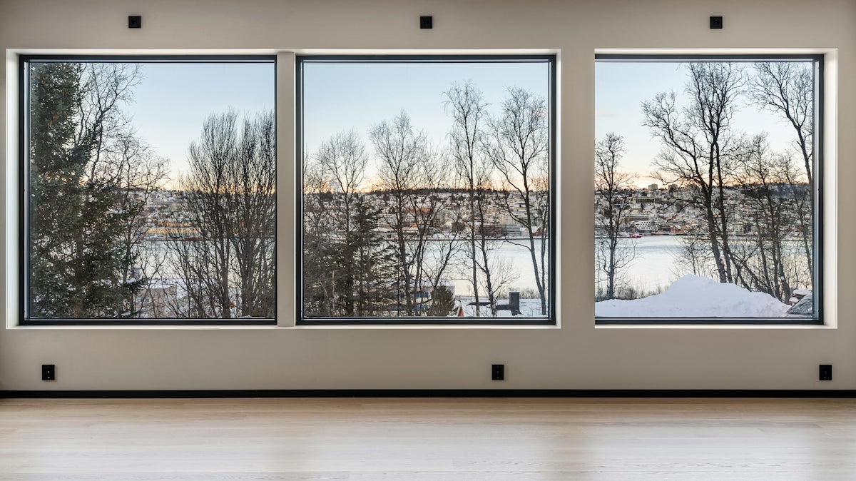 An empty room with three windows and a view of a river