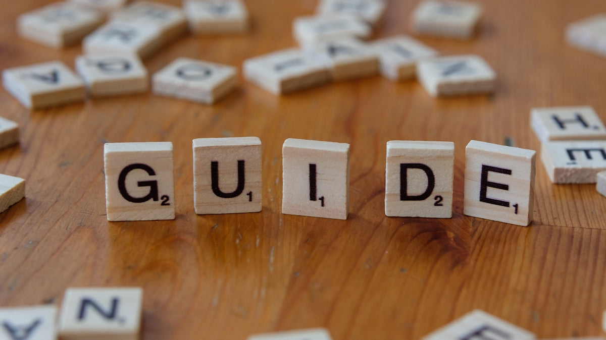 A wooden table topped with scrabble tiles spelling the word guide