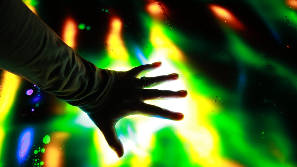 A hand touches colorful lights.