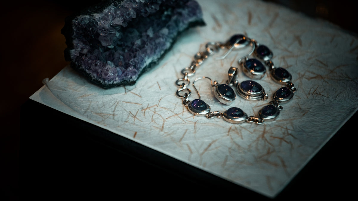 Amethyst jewelry and raw crystal on textured paper