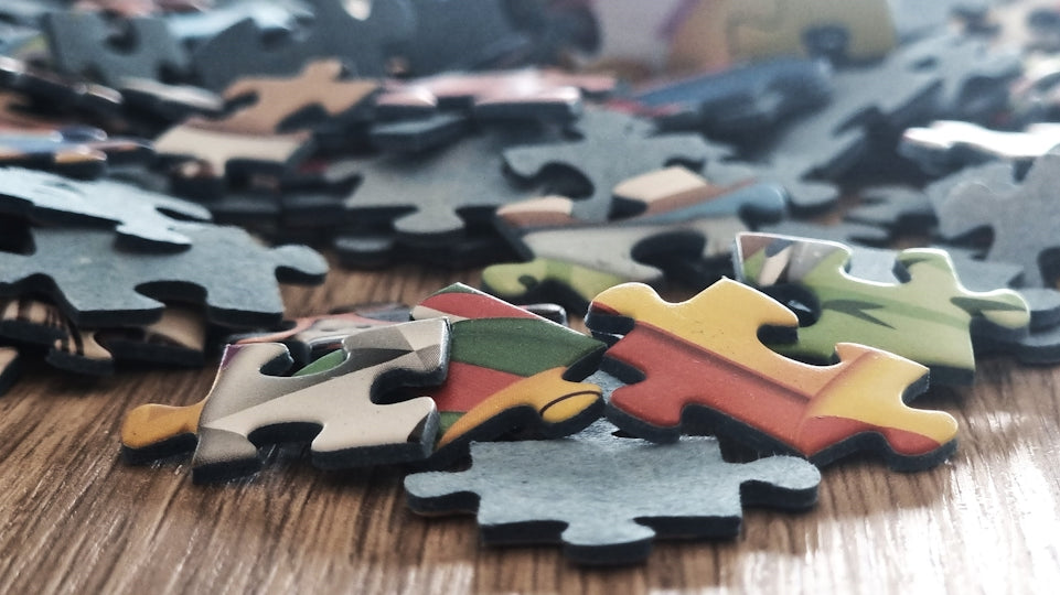 Scattered colorful puzzle pieces on a wooden surface.