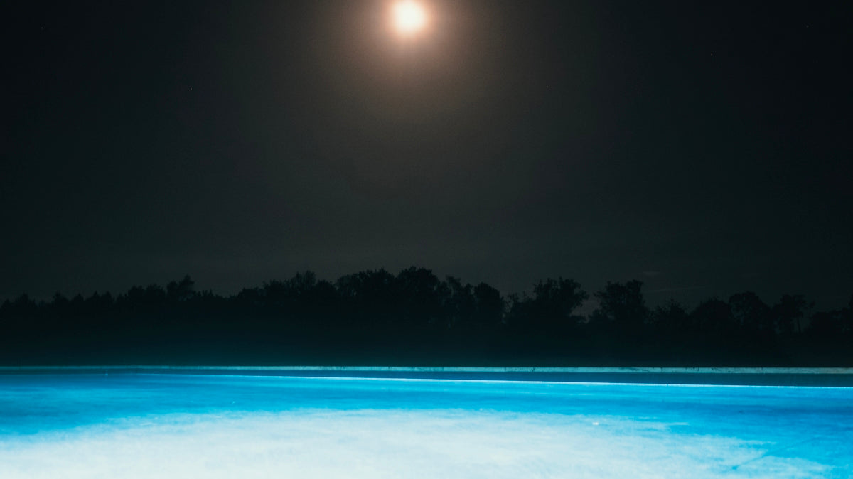 Moonlit night over a bright blue pool
