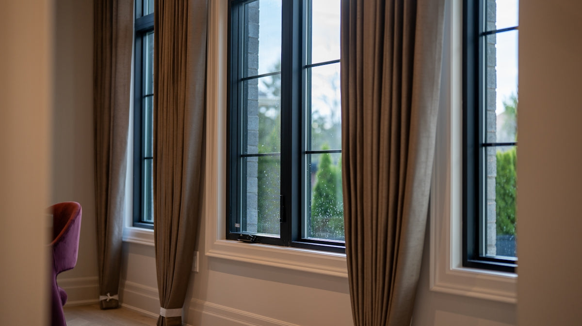 Large windows with beige curtains in a room.
