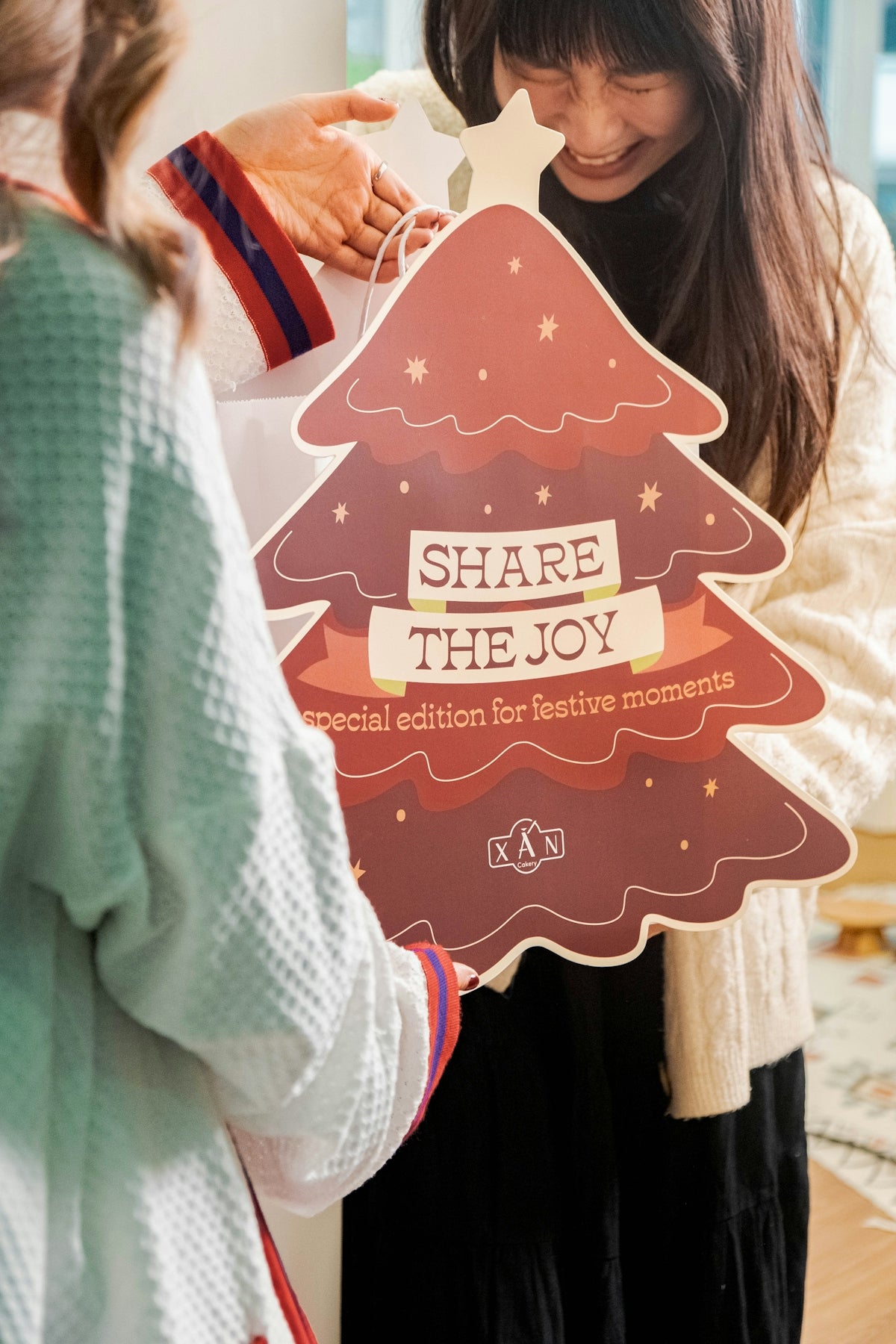 a woman holding up a cardboard christmas tree
