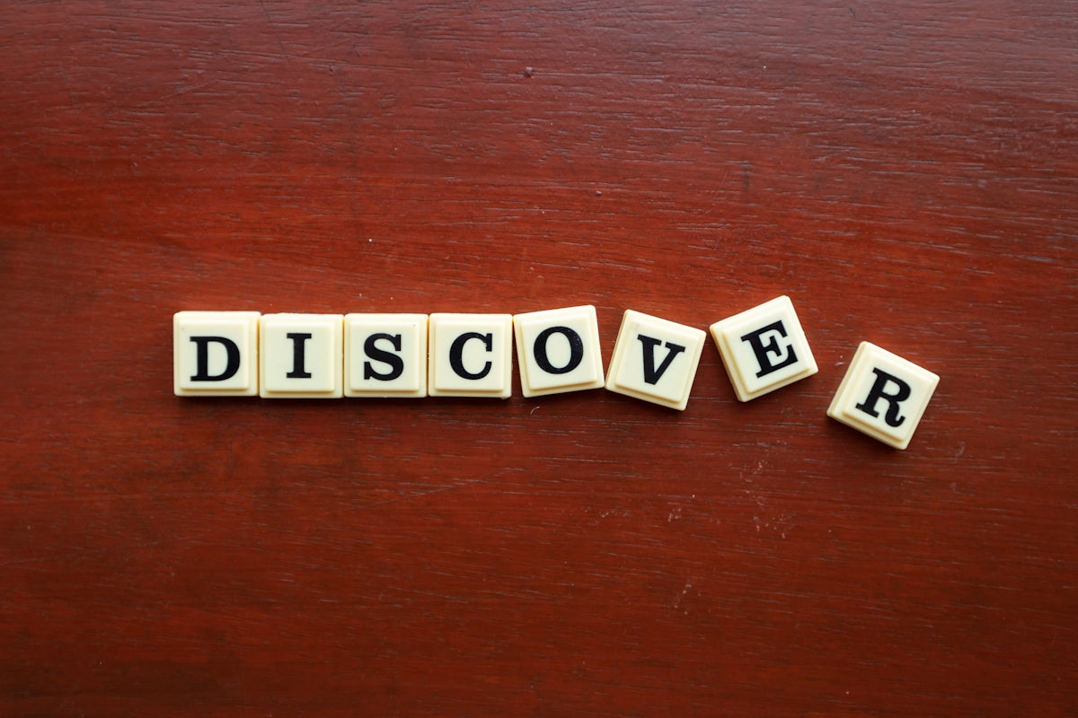 the word discovery spelled with scrabble letters on a wooden surface