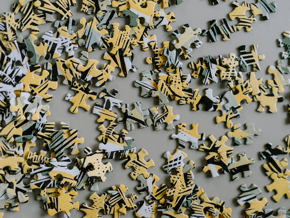 Scattered puzzle pieces with yellow and grey abstract patterns