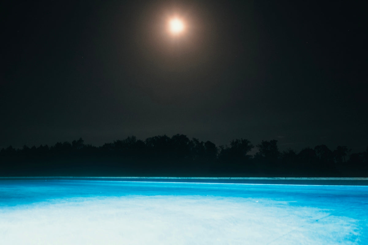 Moonlit night over a bright blue pool