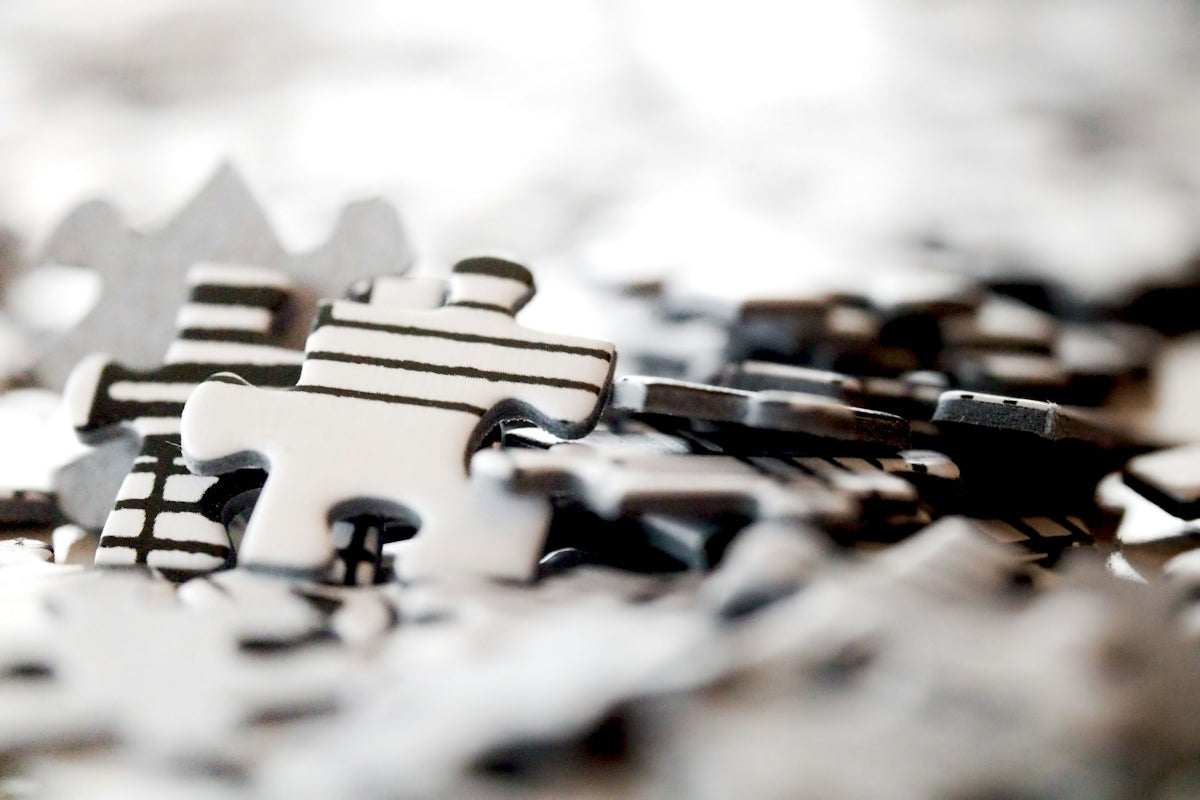 Scattered black and white jigsaw puzzle pieces