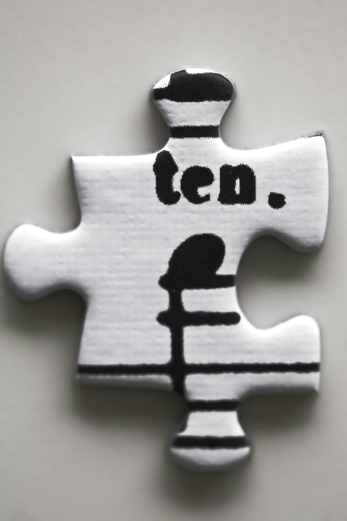 A white puzzle piece with the word ten. on it